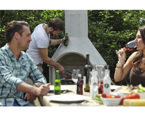 Personen grillen an einem Gartengrill und sitzen an einem Esstisch