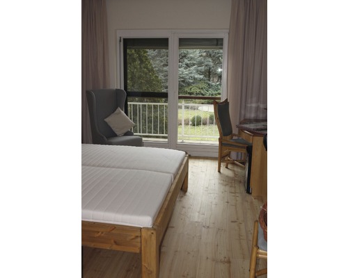 Chambre avec lit double, fauteuil et accès au balcon.