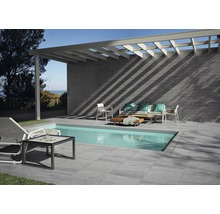 Terrasse avec piscine, sol carrelé, revêtement mural et coin salon sous une pergola.