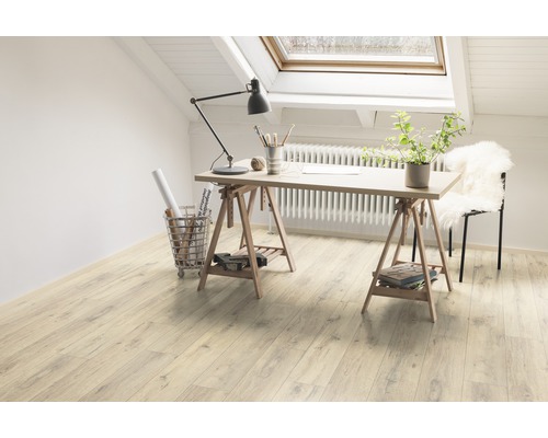 Pièce lumineuse avec bureau sur planchers en bois sous une fenêtre de toit.