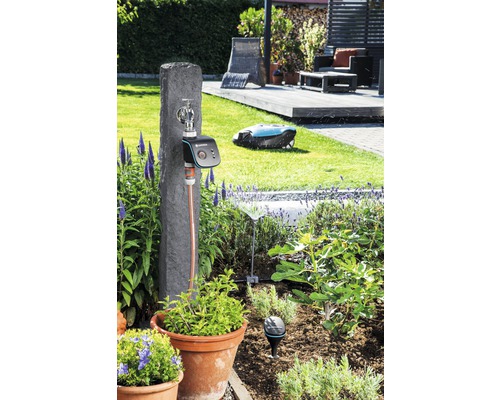 Garten mit Bewässerungssystem, Wasserhahn, Rasenmähroboter und Pflanzen