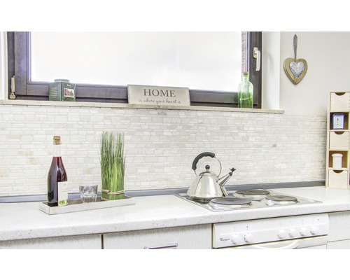 Helle Küche mit Fliesenwand, Getränken und Küchenutensilien auf der Arbeitsfläche