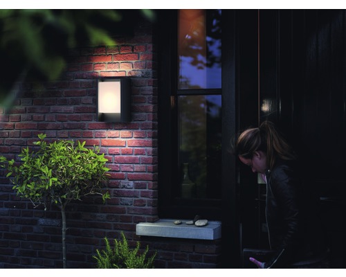 Außenansicht eines Hauses mit einer beleuchteten Wandleuchte neben einer Tür