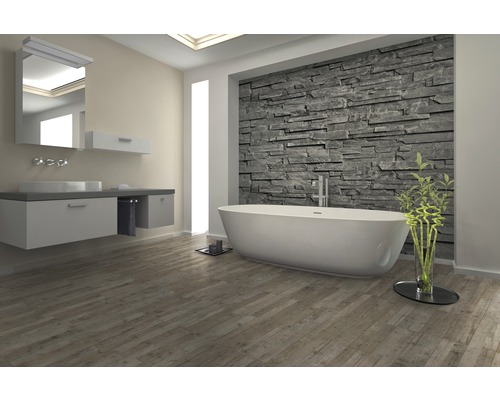 Salle de bain lumineuse avec baignoire, lavabo et mur en pierre