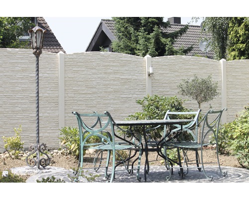 Scène de jardin avec mur en pierre, table de jardin, chaises de jardin et lanterne décorative.