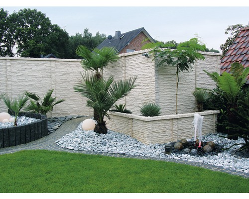 Jardin aménagé avec clôture, plantes, allée de gravier et fontaine