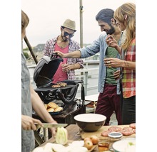 Des personnes font des grillades sur un toit avec un gril, des ingrédients et des petits pains.