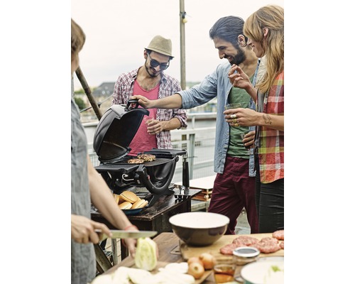 Des personnes font des grillades sur un toit avec un gril, des ingrédients et des petits pains.
