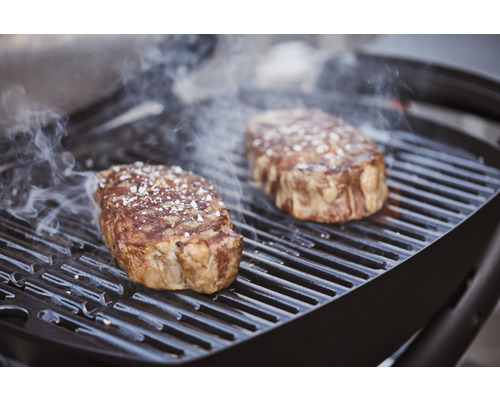 Deux steaks sur un gril avec dégagement de fumée