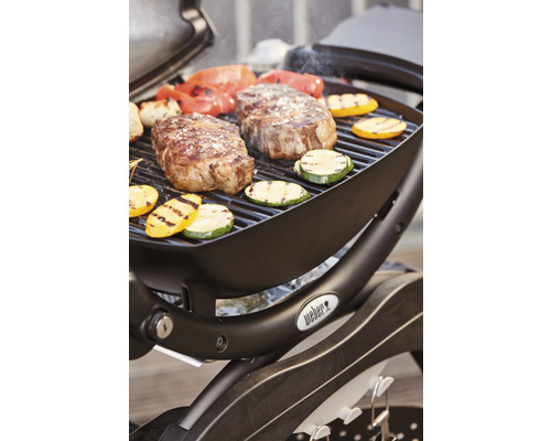Barbecue Weber avec steaks, courgettes et poivrons sur la grille