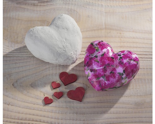 Zwei Herzen und einige kleine Holzherzen auf einem Holztisch.