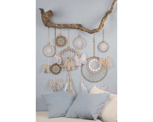 Scène décorative avec des attrape-rêves sur une branche et des coussins avec des broderies.