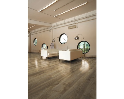 Heller Raum mit Holzboden, Sofas und runden Fenstern.