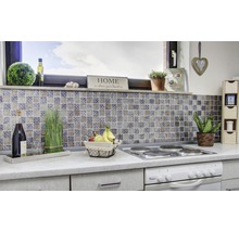 Scène de cuisine avec des carreaux de mosaïque, une plaque de cuisson, des décorations et des aliments sur un plan de travail.