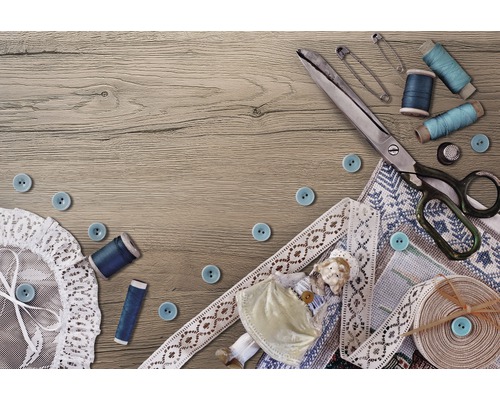 Scène de couture avec ciseaux, boutons, fil, épingles de sûreté, dentelle et poupée sur une table en bois