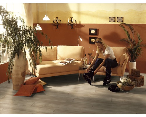 Wohnzimmer mit Sofa, Zimmerpflanzen und Frau beim Anziehen von Inlineskates