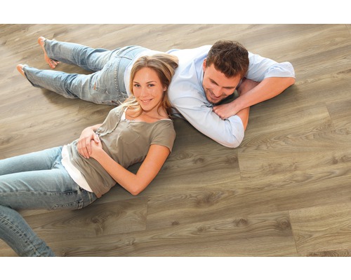 Ein Paar liegt auf einem hellen Holzlaminatboden.