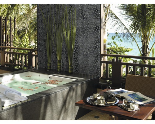 Salle de bains avec mur en mosaïque, baignoire et table sur une terrasse avec vue sur la mer