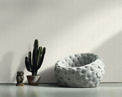 Une pièce avec un papier peint à motifs, un fauteuil, un cactus et une statue