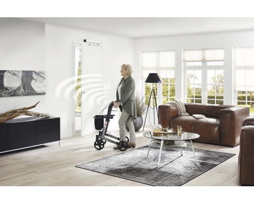 Frau mit Rollator in einem Wohnraum mit automatischem Türantrieb