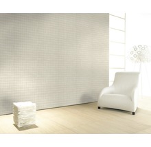 Pièce lumineuse avec papier peint à motifs, fauteuil et lampe.