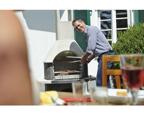 Mann grillt mit Grillzange Fleisch auf einem Gartengrill.