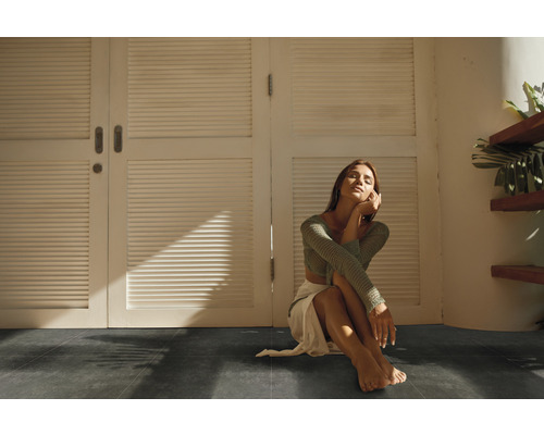 Intérieur avec sol foncé et une femme assise devant une porte blanche