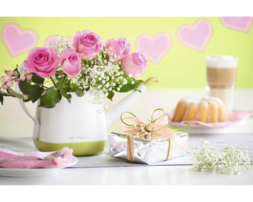 Nature morte décorative avec des roses dans un arrosoir, un cadeau et un gâteau