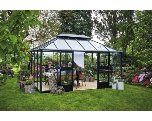 Serre avec murs et toit en verre dans le jardin, avec un groupe de personnes à l''intérieur.