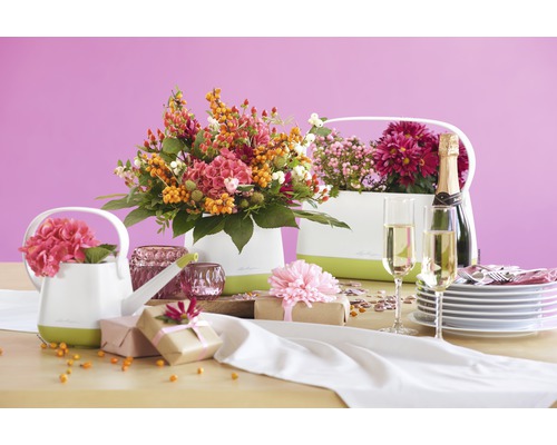 Table décorative avec arrangements floraux dans des cache-pots, cadeaux, champagne et vaisselle