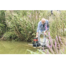 Un homme utilise une pompe d''évacuation des eaux chargées au bord d''un plan d''eau.