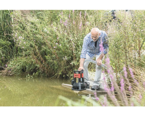 Un homme utilise une pompe d''évacuation des eaux chargées au bord d''un plan d''eau.