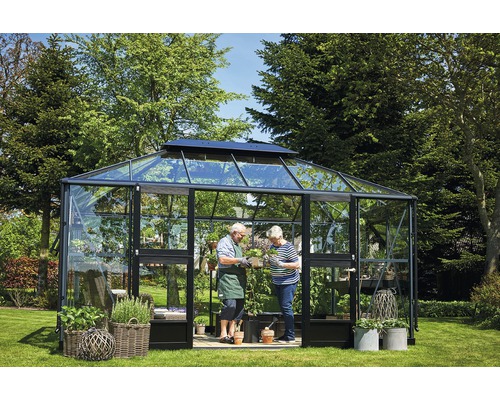 Serre avec plantes et deux personnes dans le jardin