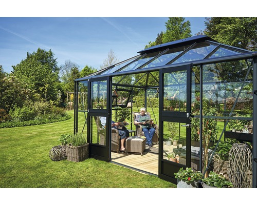 Serre avec coin salon et plantes dans le jardin