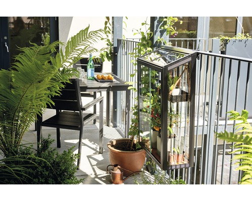 Balkonszene mit Tisch, Stuhl und einem an einem Geländer befestigten Gewächshaus