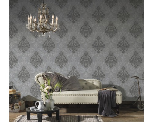 Dekorativer Raum mit einer Couch vor einer gemusterten Tapete und einer Vintage-Atmosphäre.