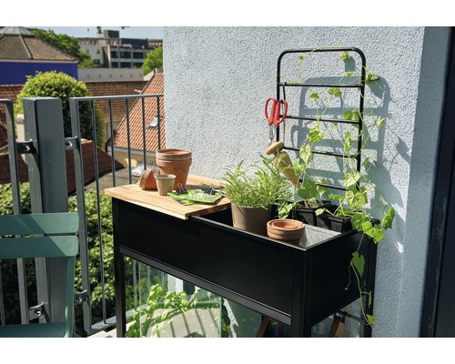 Balkonszene mit Pflanztisch, Rankhilfe, Pflanzen und Gartenzubehör