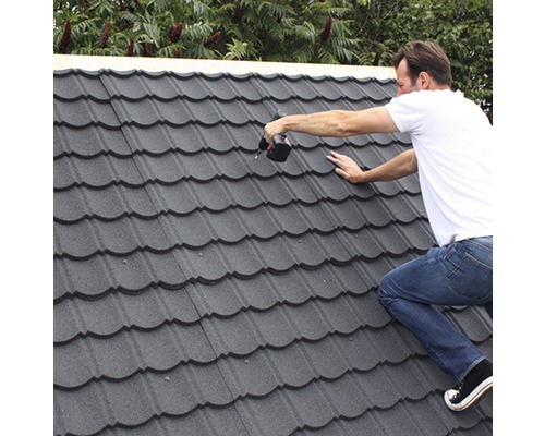 Artisan installant des tuiles métalliques avec un tournevis sans fil