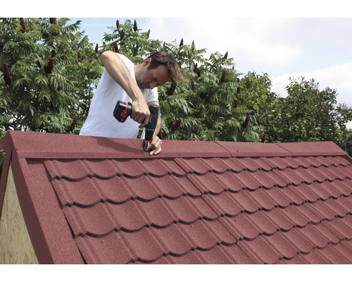 Homme montant le toit d''une cabane de jardin avec un tournevis sans fil