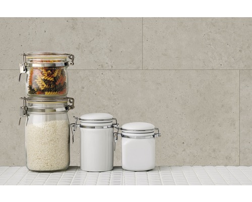 Bocaux de stockage avec pâtes, riz et récipients blancs sur une surface carrelée blanche devant un mur gris