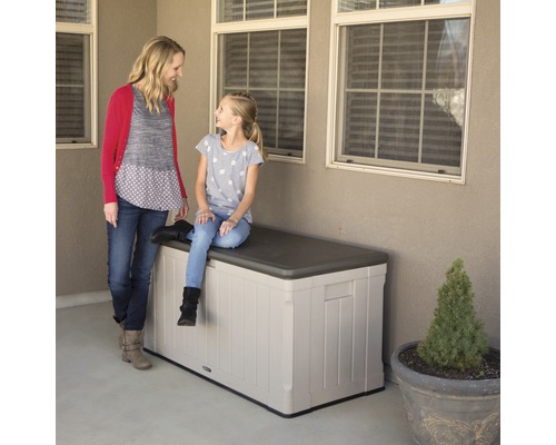 Eine Mutter steht neben einem Mädchen, das auf einer Gartenbox aus Kunststoff sitzt.