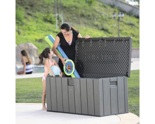 Aufnahme einer Familie, die Poolspielzeug in einer grauen Aufbewahrungsbox im Freien verstaut