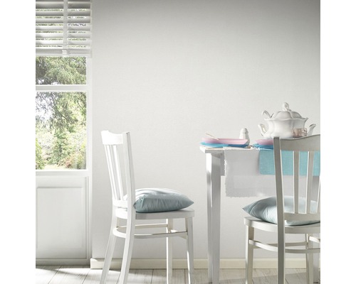 Heller Raum mit weißen Möbeln, Tisch und Stühlen in Szene gesetzt.