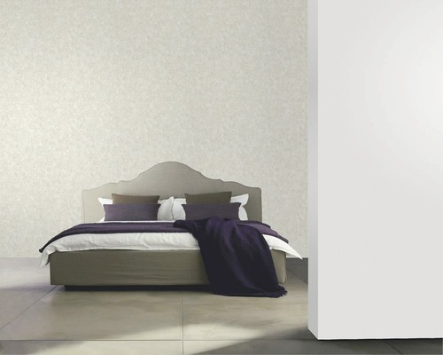 Chambre avec lit, coussins et papier peint au mur.