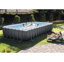 Piscine rectangulaire avec des personnes jouant et des chaises longues dans le jardin.