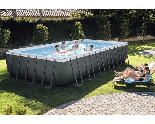 Piscine rectangulaire avec des personnes jouant et des chaises longues dans le jardin.