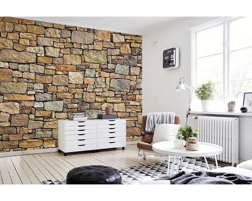 Séjour avec papier peint mural en pierre, commode, fauteuil et table basse.