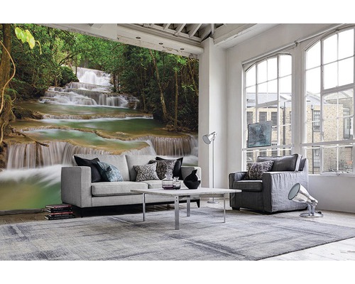 Salon avec papier peint photo d''une cascade dans une forêt, canapé clair, fauteuil et tapis.