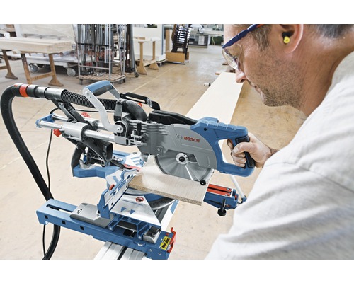 Une personne utilise une scie à onglet radiale Bosch pour couper une pièce.