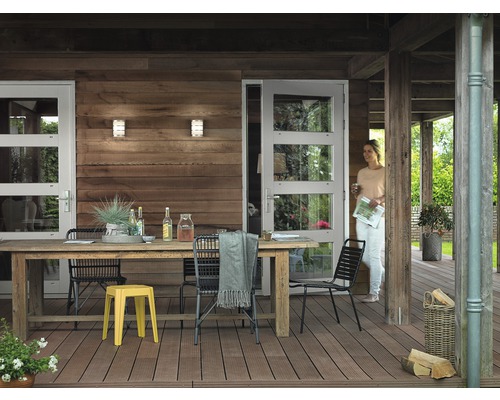 Holzterrasse mit Tisch, Stühlen und einer Frau, die eine Tür betritt